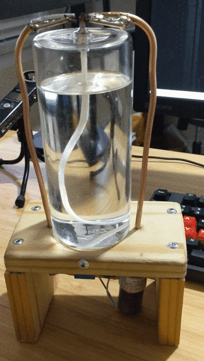 Arc jumping between two copper tube tips above the wick of a glass oil candle, lighting it