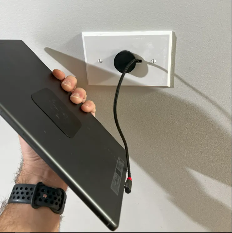 Printed keystone plate on the wall with the magnet and right-angle cable, tablet held beside it